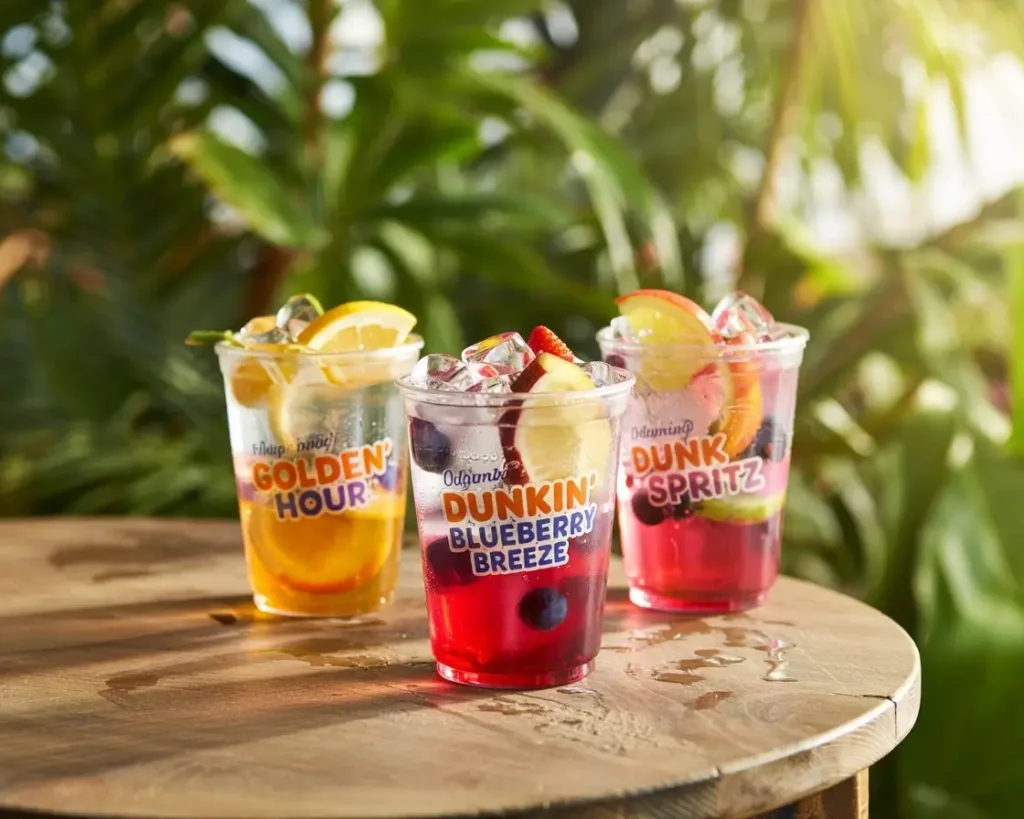 Three vibrant Dunkin Refreshers—Golden Hour, Blueberry Breeze, and Pink Spritz—iced and ready to refresh under summer sunlight.